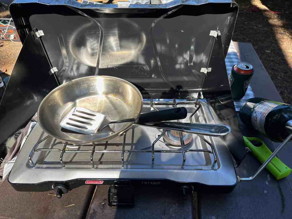 A camp stove and cooking setup ready to be cleaned after another delicious camp meal. Learn how to clean dishes while camping.