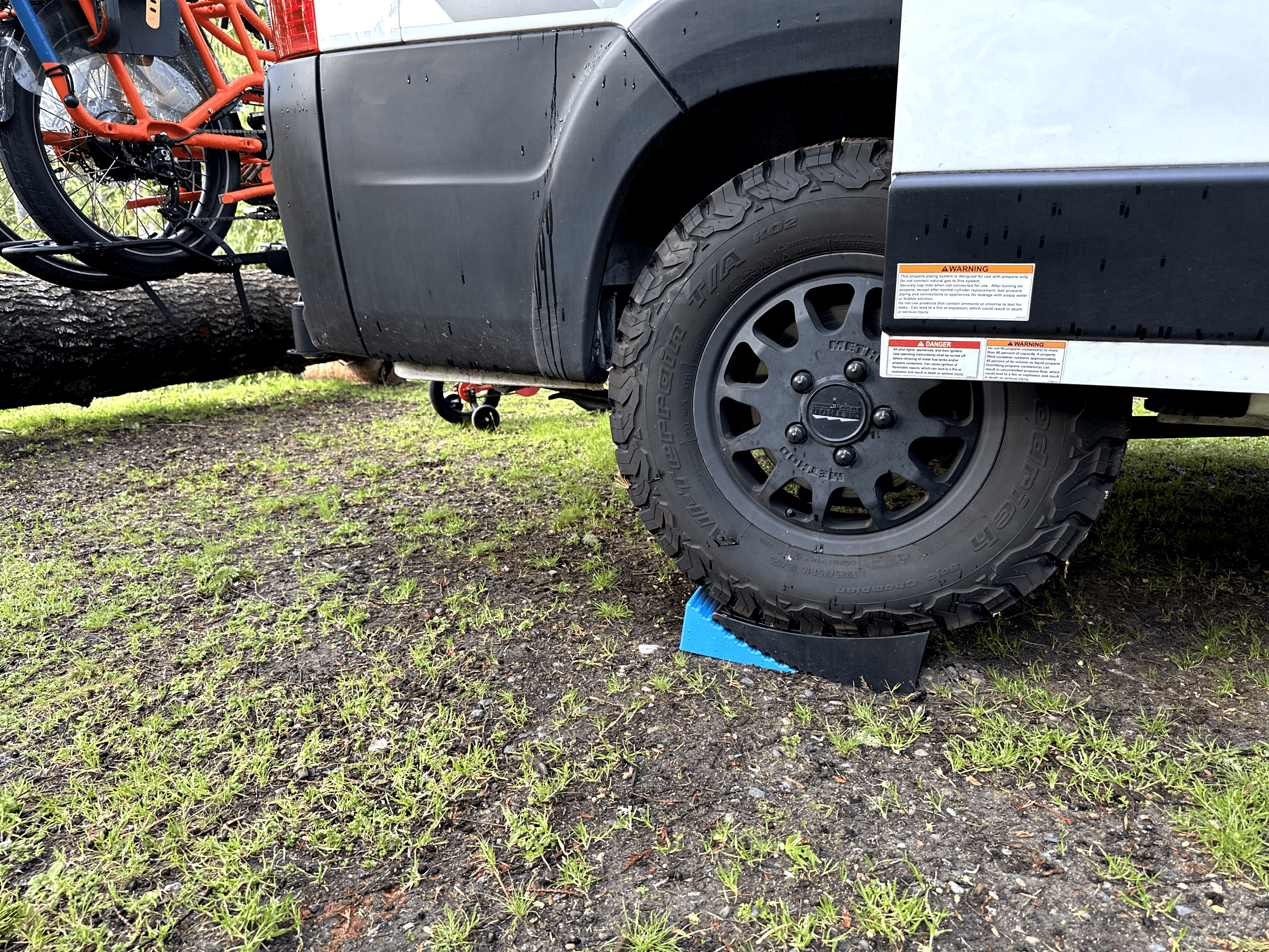 Off-road vehicle with Firestone tires and bike rack in natural setting.