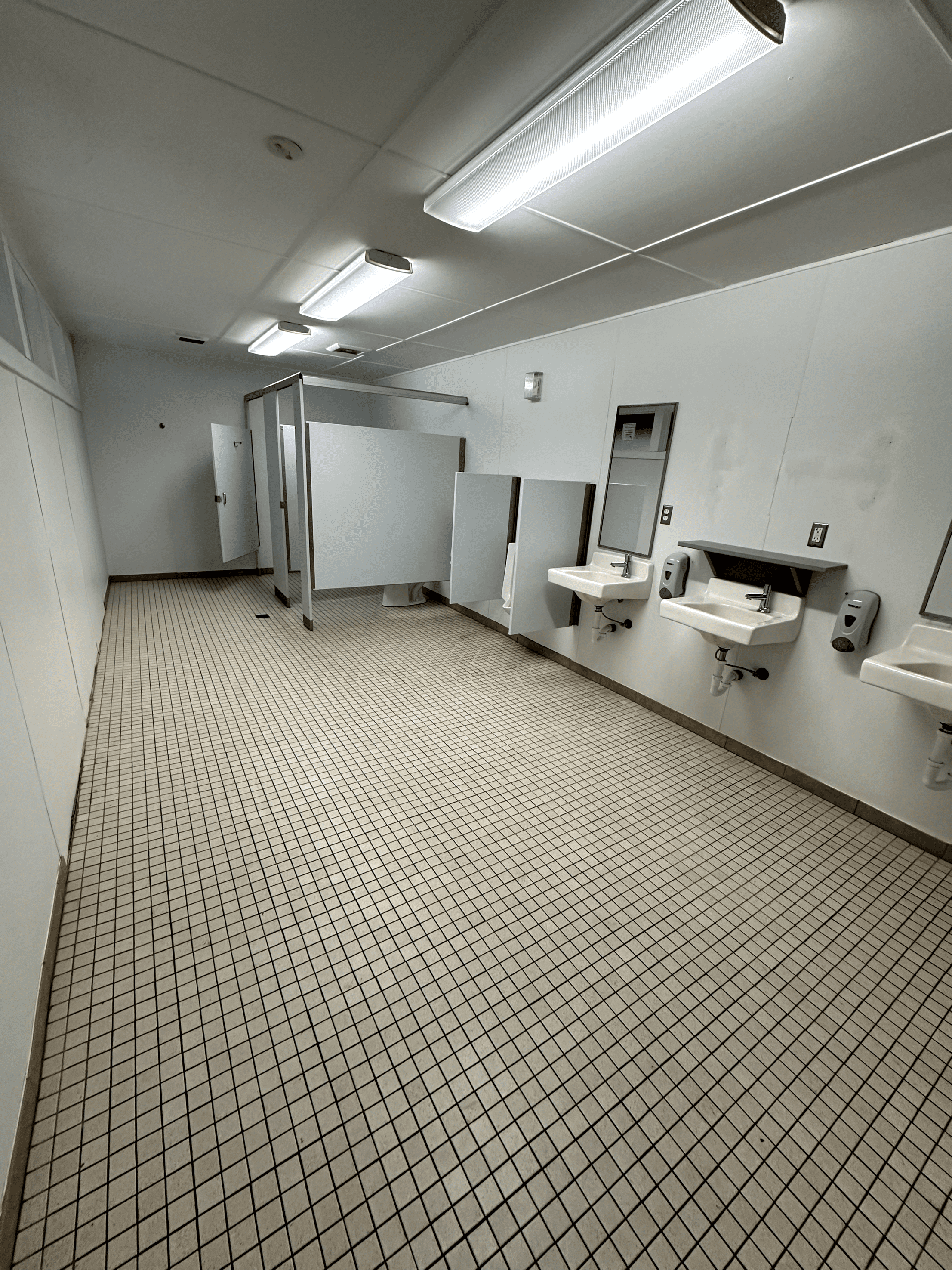 Clean and functional public restroom with sinks, stalls, and bright lighting.