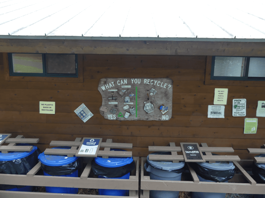 Outdoor recycling station with educational signage promoting sustainable waste management.