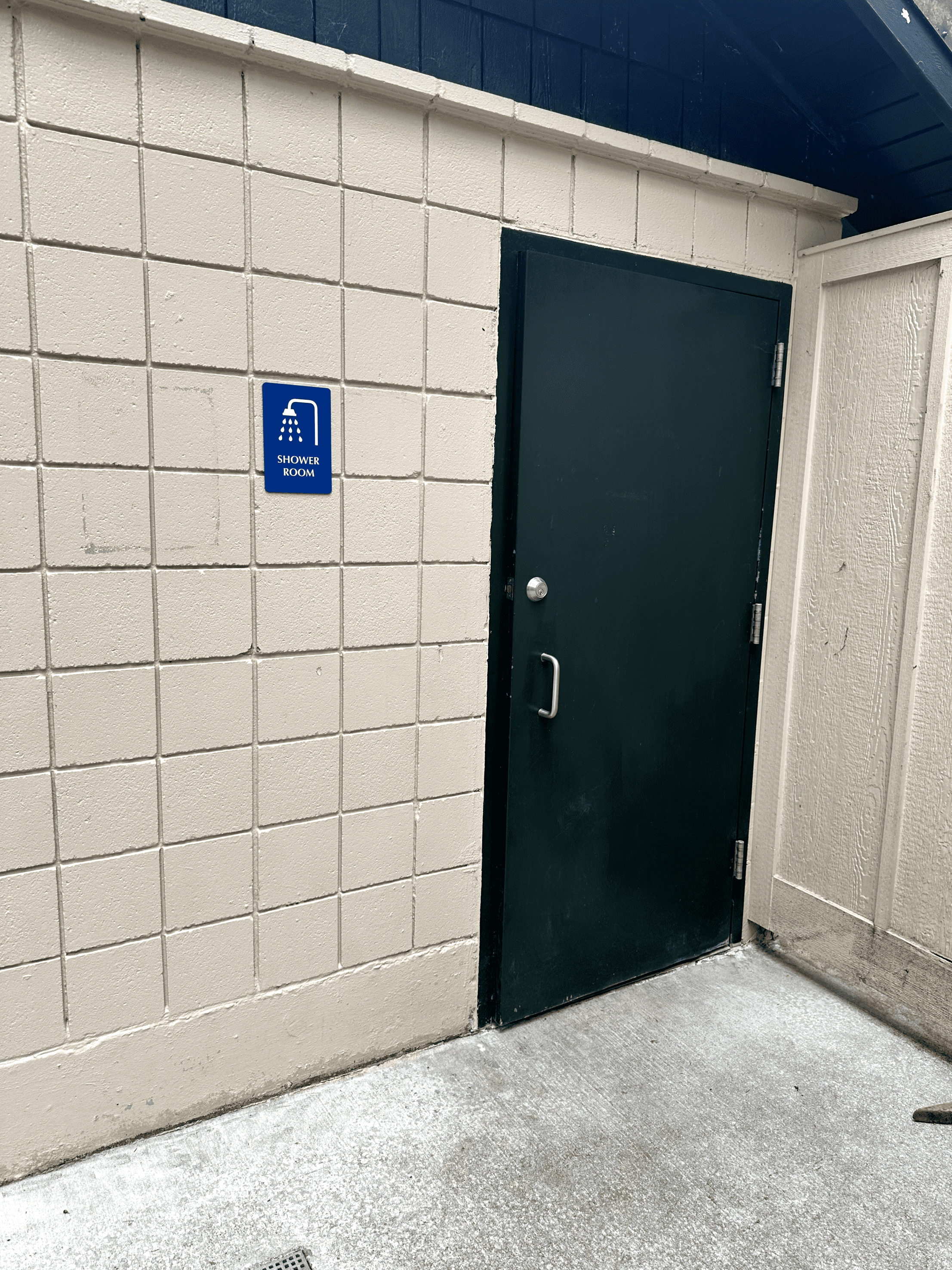 Entrance to outdoor shower room facility at concrete block building.