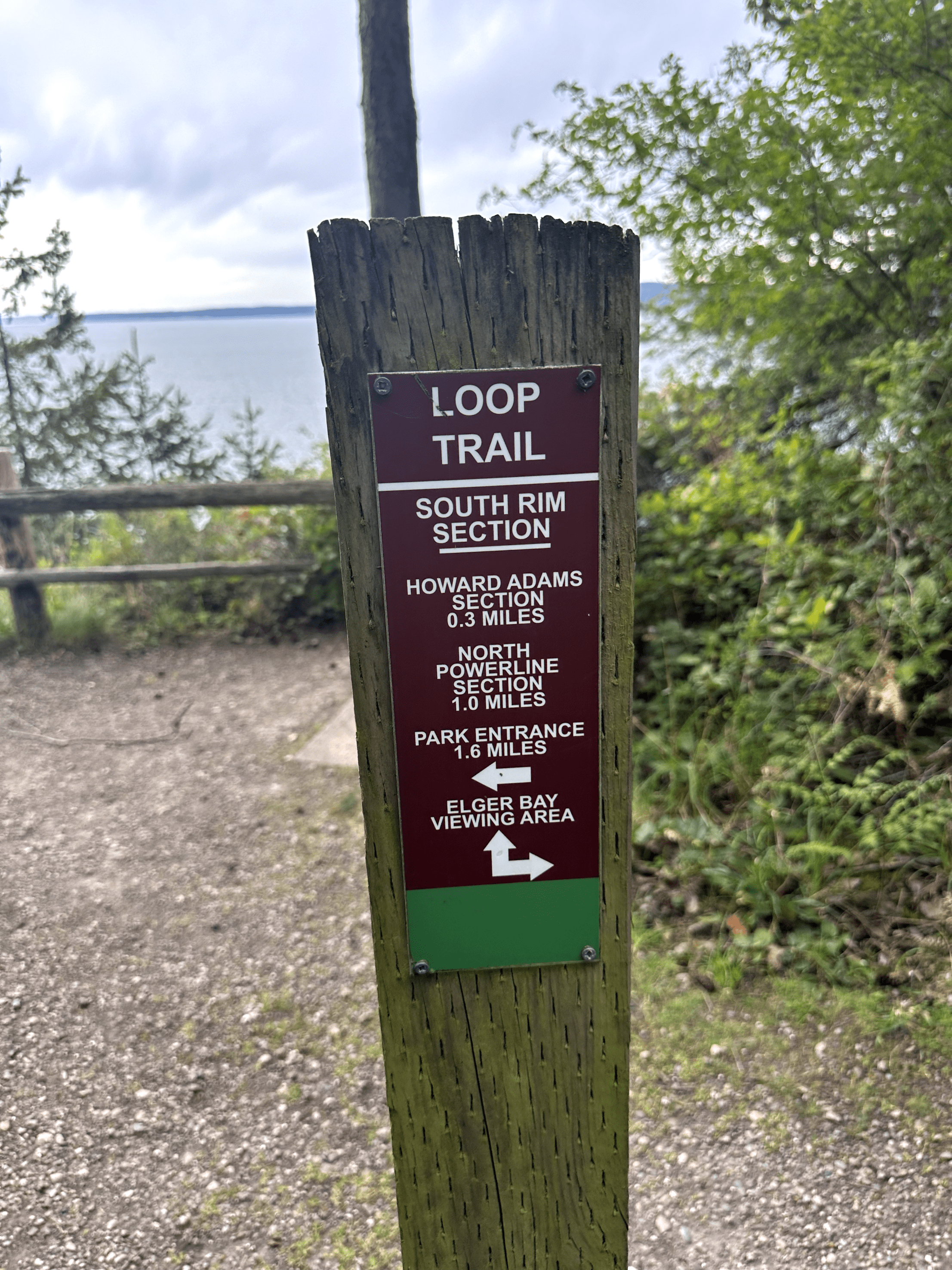 Weathered wooden trail signpost in lush natural setting, offering directions for visitors.