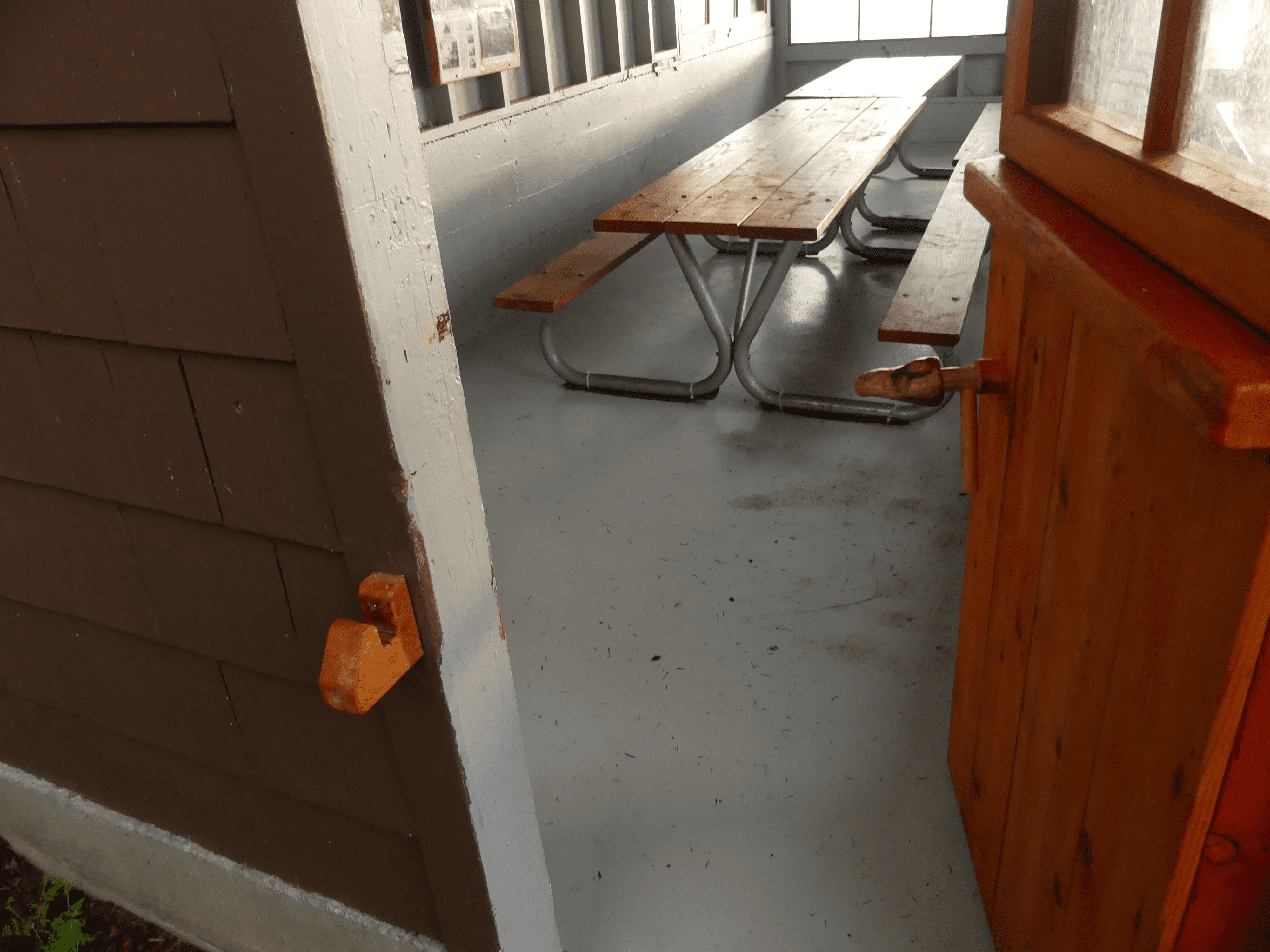 Rustic wooden table in a workshop setting with concrete floor.